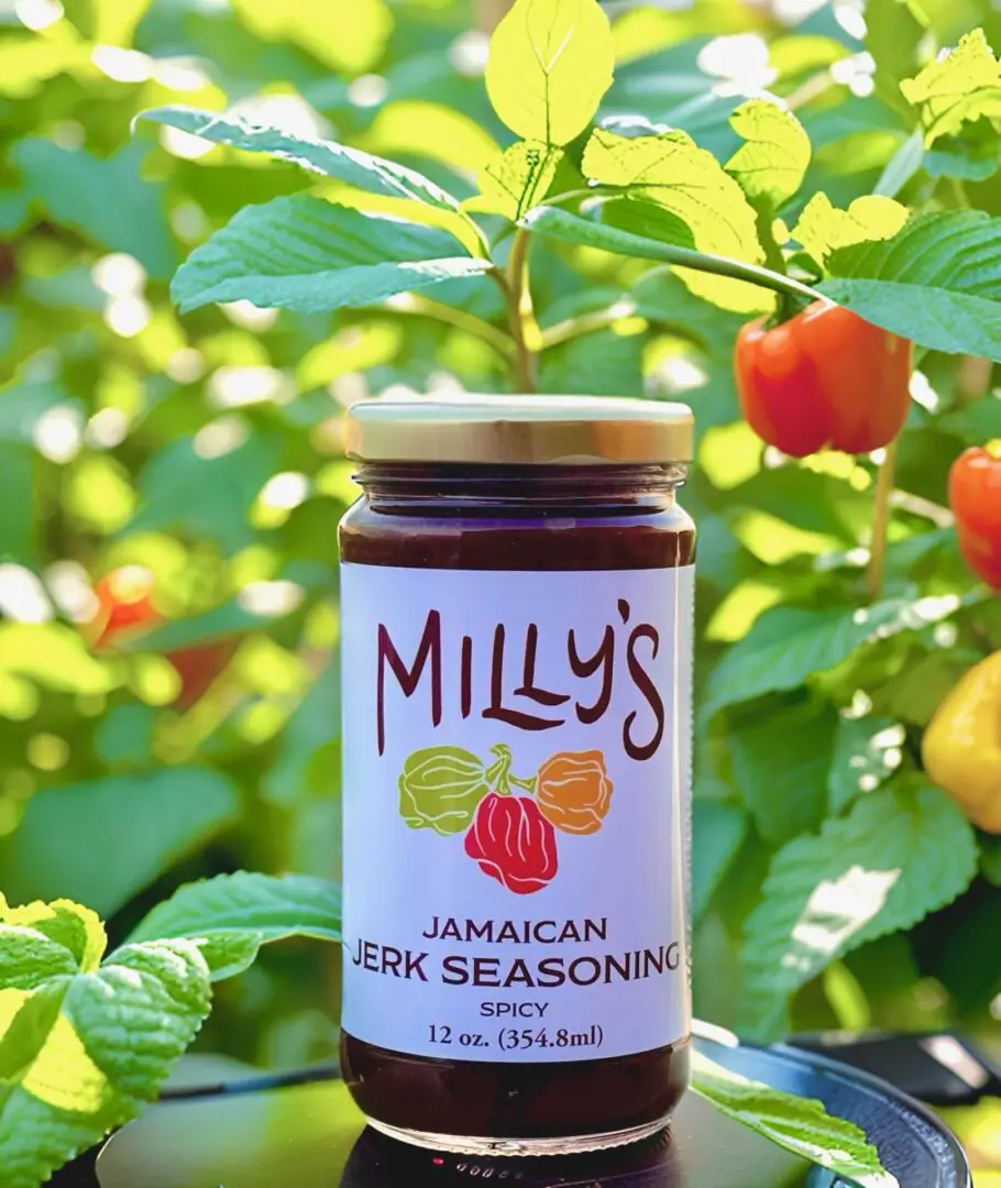 A jar of jelly sitting in front of some fruit.